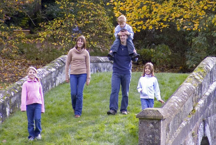 A family of 5 walking across a stone bridge in autumn